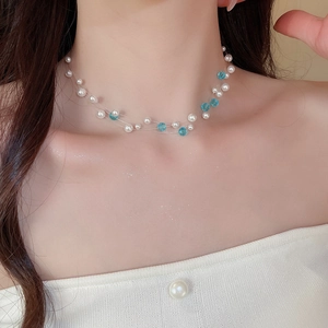 Close-up of multilayered pearl and blue faceted crystal bead necklace on model