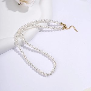 Detailed view of pearl necklace with gold clasp on minimalist white pedestal display