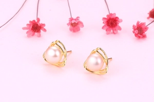 Macro view of triangle S925 silver earrings with pink freshwater pearls and gold finish