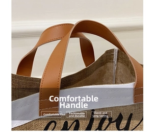 Close-up of brown leather handle and stitching detail on a burlap tote bag