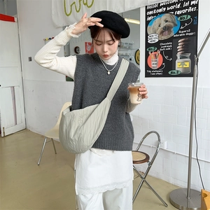 Detailed view of a light green nylon dumpling bag paired with a minimalist knit vest