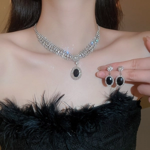 Close-up of sparkling zircon necklace and earrings set with oval black center stones