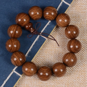 Macro view of natural grain on dark brown sandalwood beads with traditional knot