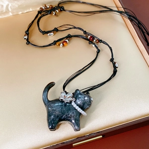 Dettaglio del ciondolo a gatto nero con collana di perle in una scatola regalo dorata