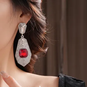 Vintage silver earrings featuring large red crystals and pavé diamonds on a model