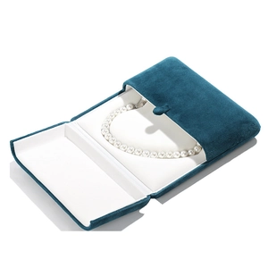 Dark blue velvet jewelry box with heart-shaped design holding a white pearl necklace