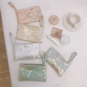 Flat lay of jacquard rose pattern cosmetic bags in various colors on a white background