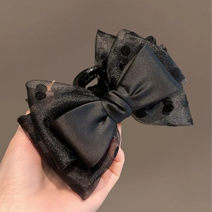 Elegant black satin and polka dot tulle bow hair claw clip shown in hand-held view