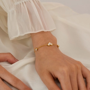 Close-up of a gold heart bracelet with white shell inlay and zircon accents on the wrist