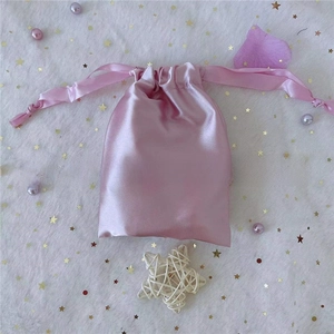 Close-up of pink satin drawstring bag for jewelry and gift packaging with silk ribbon