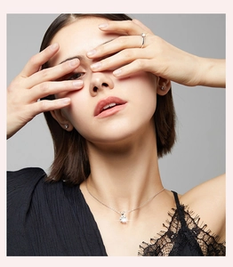 Detailed close-up of a model wearing a classic six-prong moissanite necklace and silver ring