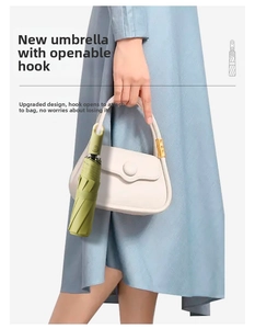 Detail showing fruit green folding umbrella with built-in hook handle on a white bag