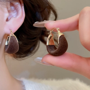 Macro shot of dark brown velvet U-shape earring with gold clasp details and on-ear look