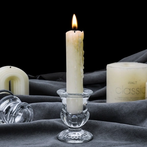 European ribbed glass candle holder with lit white pillar candle on dark velvet