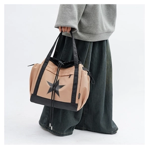 Crossbody tote bag showing model wearing cream nylon bag with black star detail