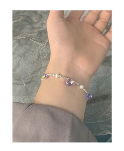 Detailed view of elegant purple crystal and white pearl bracelet on wrist with silver chain