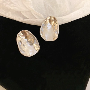 Macro view of silver liquid metal irregular geometric earrings on black velvet