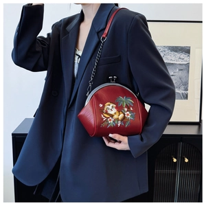 Detailed close-up of a red shell bag featuring intricate squirrel embroidery and metal clasp