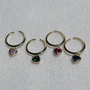 Detail of four gold open rings with dangling heart-shaped crystals in various colors