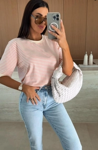 Détail d'un t-shirt à rayures roses et blanches avec un jean bleu clair délavé