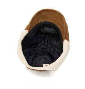 Detail of brown suede newsboy cap featuring plush fleece trim and quilted thermal lining