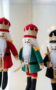 Close-up of three plush Nutcracker soldier ornaments with sequins and gold tassels