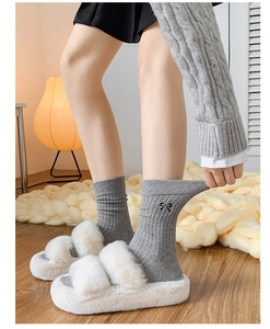 Detail of gray cotton mid-calf socks with black bow embroidery and chic striped texture