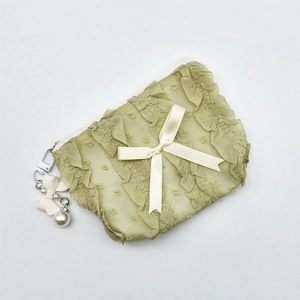 Detail view of light green lace cosmetic bag with polka dots and ruffled edges