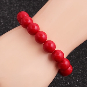 Vue détaillée d'un bracelet de perles rouges polies sur poignet avec fini brillant
