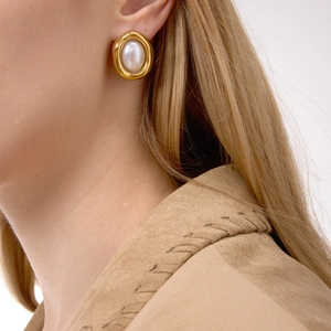 Close-up of vintage 18K gold-plated earrings with large resin pearls on a model