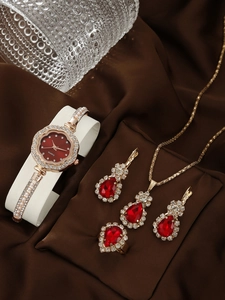 Macro shot of gold quartz watch and jewelry set with red gemstones on silk background