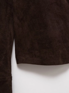 Detailed macro texture of dark brown faux suede fabric and precise stitching on the sleeve