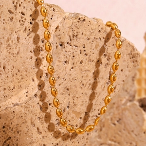 Close-up of golden oval bead chain necklace on a natural stone background