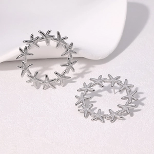 Detailed view of silver starfish hoop earrings in a circular nautical link pattern