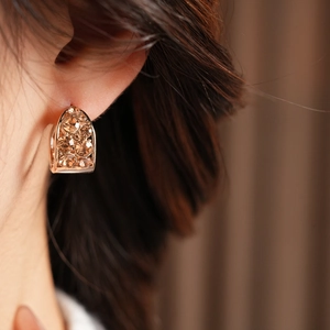 Gros plan de boucles d'oreilles vintage dorées en U avec zircons champagne sur l'oreille