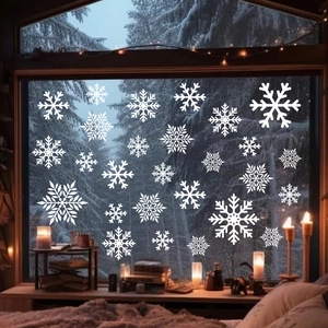 Close-up of white snowflake window stickers on glass against a snowy night forest backdrop