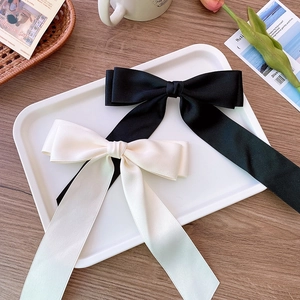 Satin ballet bow hair clips in black and cream on a decorative tray for elegant styling