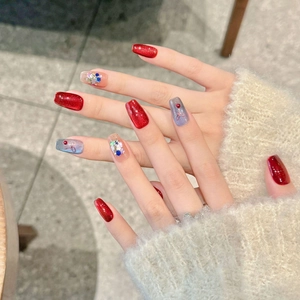 Macro shot of festive red cat-eye press-on nails with glitter, ribbons, and rhinestones