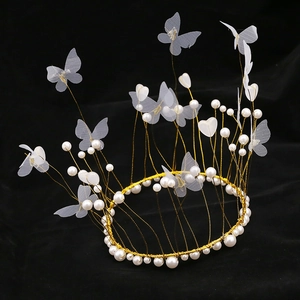Elegant gold wire crown featuring white pearls and delicate butterflies on a black background