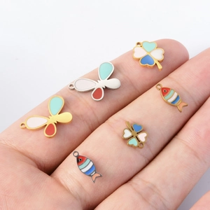 Colorful enamel clover butterfly and fish charms for DIY jewelry making on fingertips