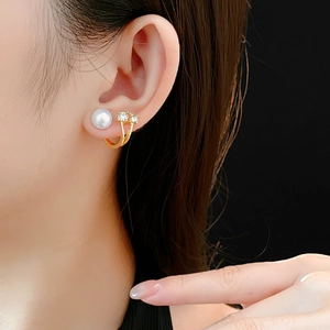 Vue macro de boucles d'oreilles perles et diamants dorées portées sur l'oreille