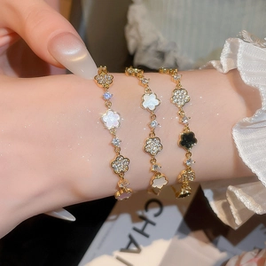 Detail of elegant gold-toned bracelets with clover flower charms and cubic zirconia stones