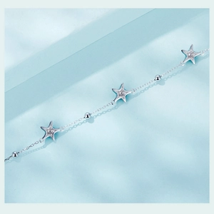 Macro shot of s925 silver star bracelet with hollow star charms on light blue background