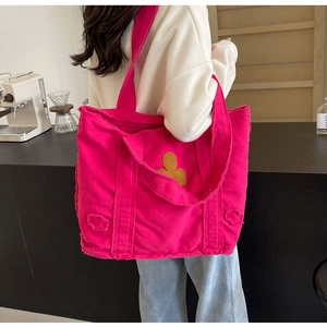 Detail of rose red canvas tote bag with frayed edges and yellow floral patch decoration