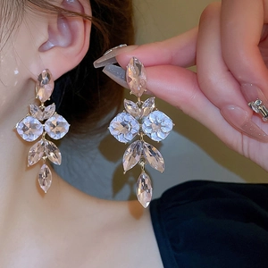 Close-up of model wearing long tassel earrings with sparkling crystals and gold finish