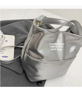 Detail of silver tote bag showing its metallic pleated texture and fine shoulder strap