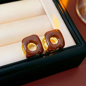 Macro view of French vintage gold square earrings with brown enamel and cutout detail