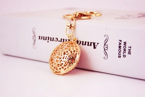 Detail of a hollow golden crystal ball keychain resting on a book with soft lighting