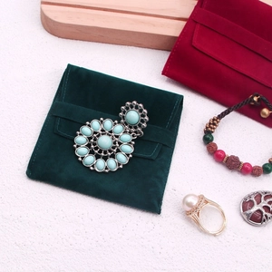 Detail of velvet jewelry pouch with pearl ring and vintage gemstone brooch display