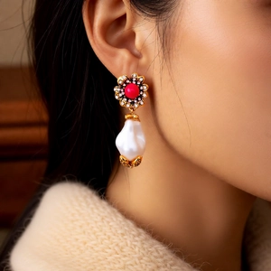 Nahaufnahme von Vintage-Ohrringen mit rotem Kristall und Barockperle am Modell